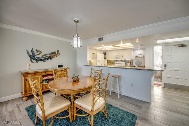 dining space with light hardwood / wood-style flooring and crown molding