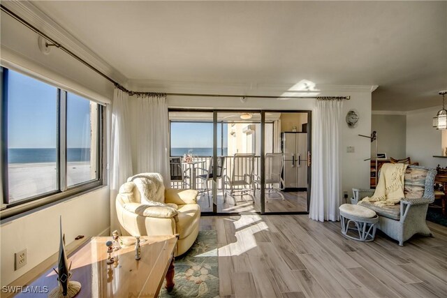 sitting room with crown molding, a water view, and light hardwood / wood-style floors