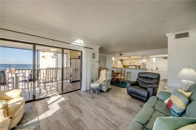 living room with a water view, light hardwood / wood-style flooring, and ornamental molding