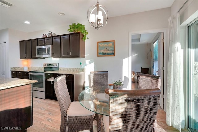 kitchen featuring dark brown cabinetry, a chandelier, decorative light fixtures, appliances with stainless steel finishes, and light wood-type flooring