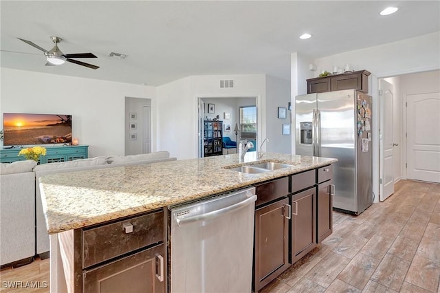 kitchen featuring a kitchen island with sink, sink, ceiling fan, light wood-type flooring, and appliances with stainless steel finishes