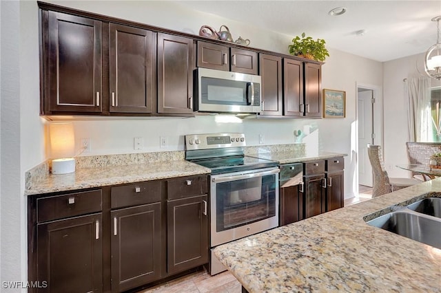 kitchen featuring dark brown cabinets, stainless steel appliances, light stone counters, and sink