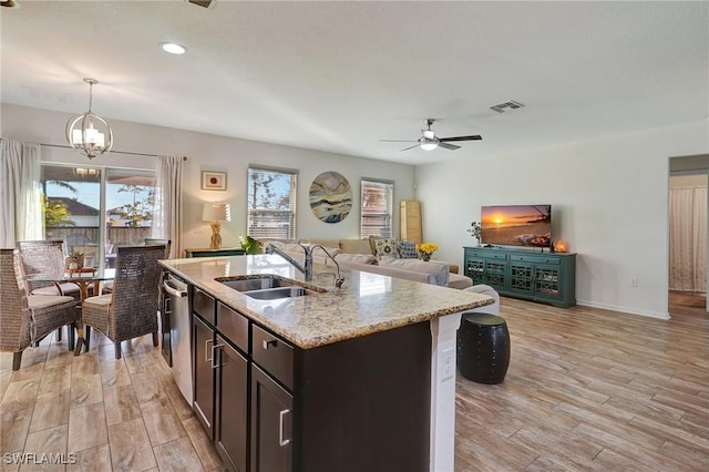 kitchen with sink, hanging light fixtures, light hardwood / wood-style flooring, an island with sink, and dark brown cabinetry