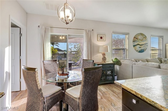 dining area featuring a notable chandelier, plenty of natural light, and light wood-type flooring