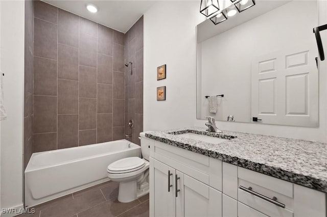 full bathroom with tile patterned floors, vanity, tiled shower / bath combo, and toilet