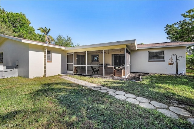 back of property featuring a sunroom and a lawn