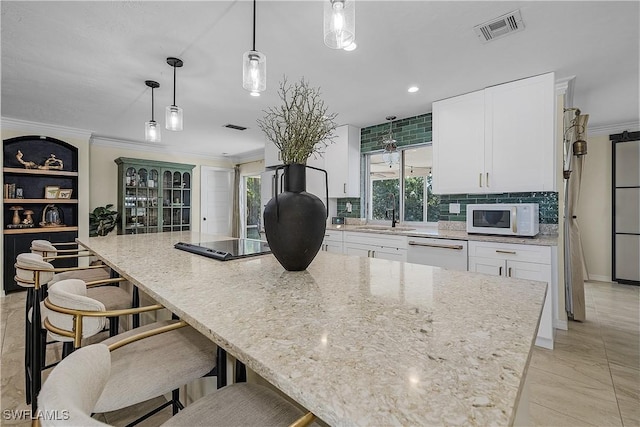 kitchen with crown molding, dishwasher, white cabinets, and hanging light fixtures