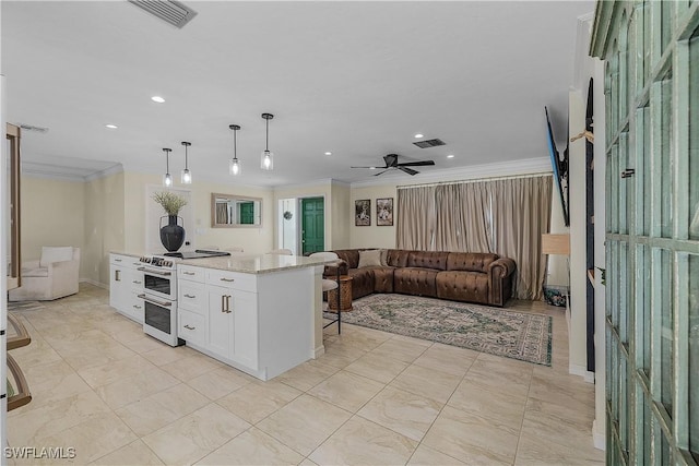 kitchen featuring ceiling fan, decorative light fixtures, range, a center island, and white cabinetry