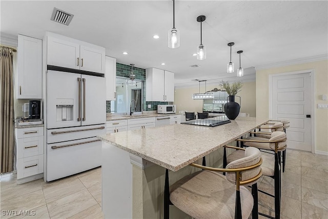 kitchen featuring white cabinets, a kitchen island, white appliances, and pendant lighting