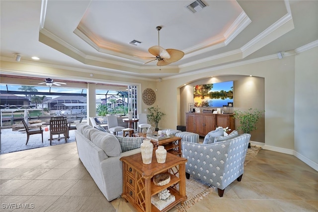 living room featuring ornamental molding, ceiling fan, and a raised ceiling