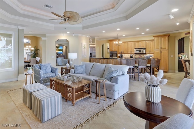 living room with crown molding, ceiling fan with notable chandelier, and a tray ceiling