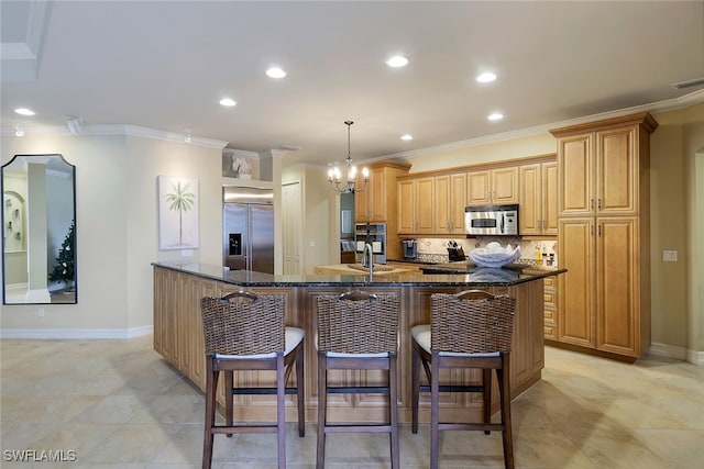 kitchen with decorative light fixtures, appliances with stainless steel finishes, ornamental molding, and dark stone countertops