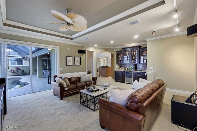 living room featuring light colored carpet, bar, crown molding, and wine cooler