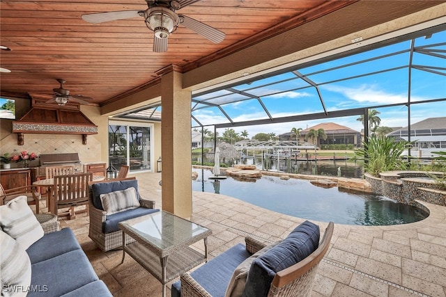 view of patio / terrace with an in ground hot tub, an outdoor kitchen, outdoor lounge area, a water view, and a lanai