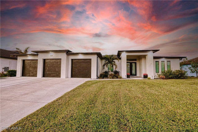 view of front facade with a lawn, a garage, and french doors