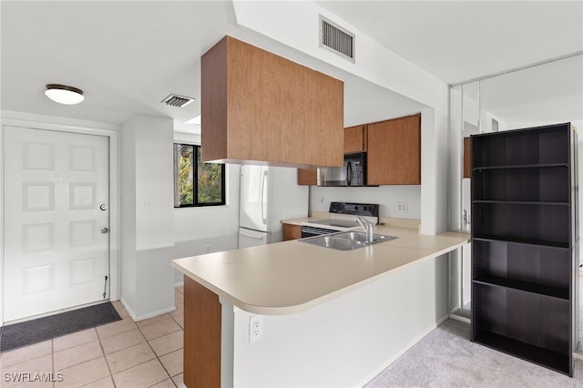 kitchen with stainless steel range with electric cooktop, white refrigerator, sink, light tile patterned floors, and kitchen peninsula