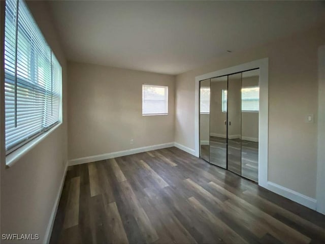 unfurnished bedroom with dark hardwood / wood-style floors and a closet