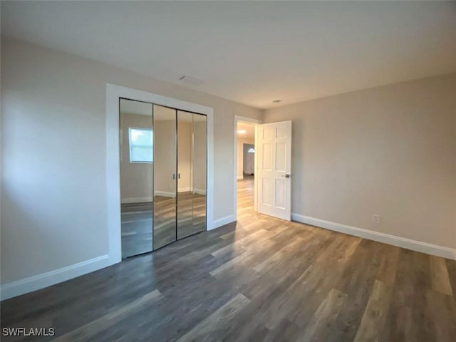 unfurnished bedroom with a closet and dark wood-type flooring