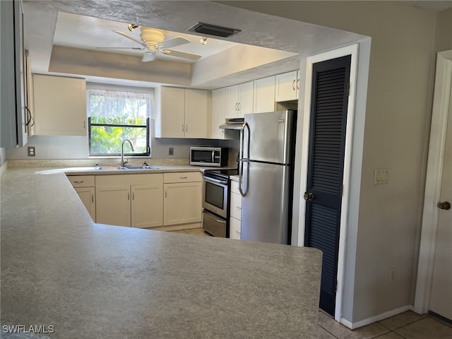 kitchen featuring stainless steel appliances, a raised ceiling, ceiling fan, sink, and light tile patterned flooring