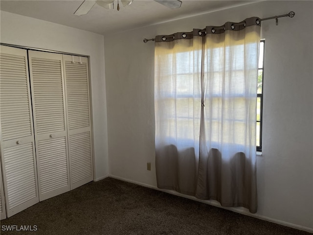 unfurnished bedroom featuring ceiling fan, a closet, and dark carpet