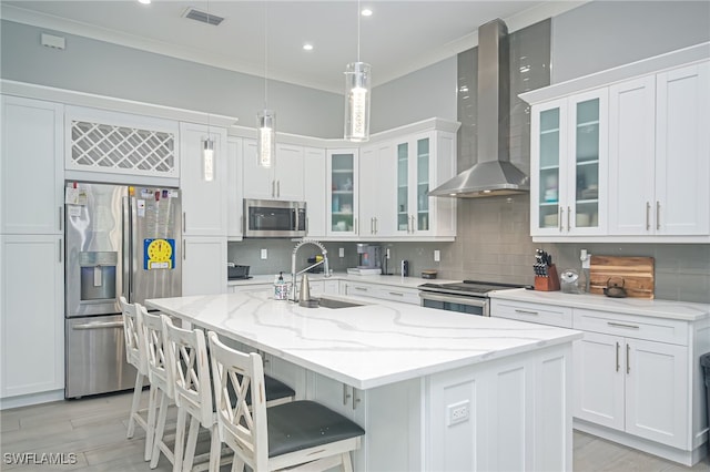 kitchen with appliances with stainless steel finishes, sink, a kitchen island with sink, and wall chimney range hood