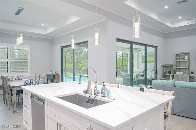 kitchen with light stone countertops, sink, a center island with sink, dishwasher, and white cabinetry