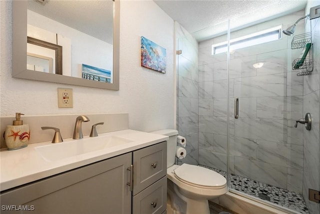 bathroom featuring a shower with door, vanity, a textured ceiling, and toilet