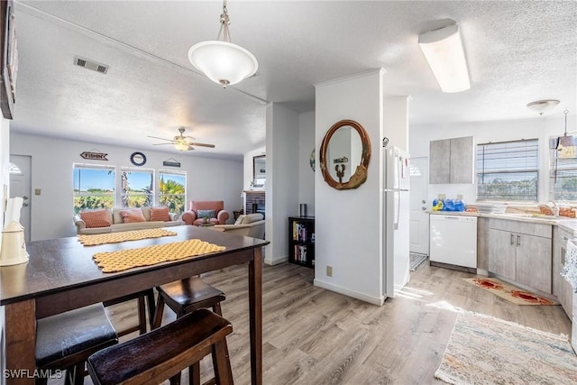 kitchen featuring white appliances, sink, a brick fireplace, ceiling fan, and a textured ceiling