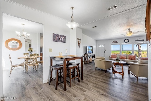 dining room with ceiling fan with notable chandelier, a textured ceiling, and hardwood / wood-style flooring