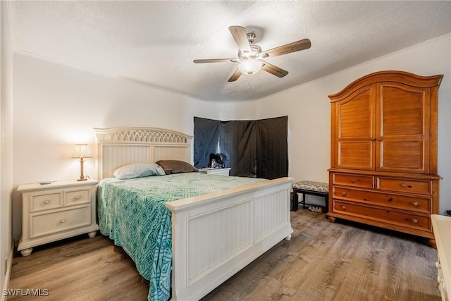 bedroom featuring ceiling fan, wood-type flooring, and a textured ceiling