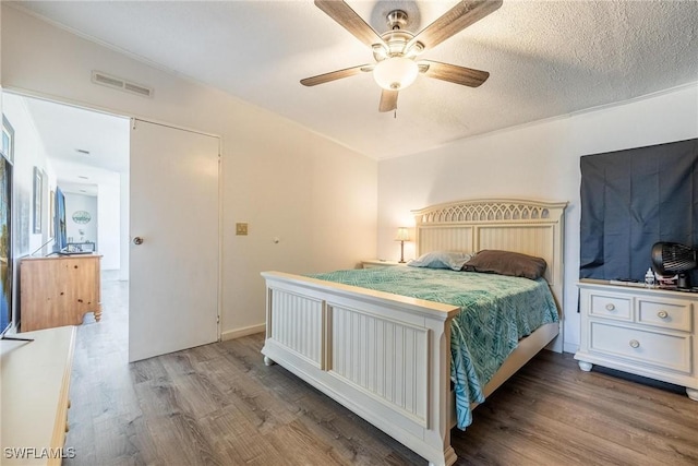 bedroom featuring ceiling fan, wood-type flooring, and a textured ceiling