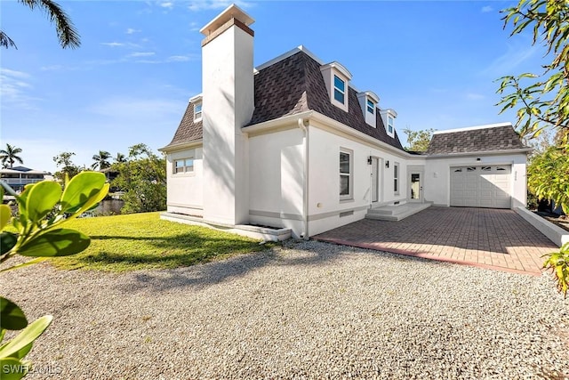 back of house featuring a garage and a lawn