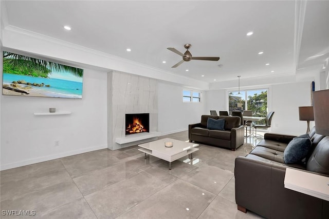 living room with ceiling fan, ornamental molding, a premium fireplace, and a raised ceiling