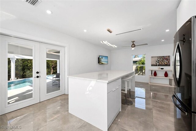 kitchen featuring ceiling fan, french doors, stainless steel fridge, decorative light fixtures, and white cabinets