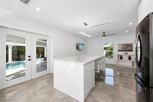 kitchen featuring white cabinetry, hanging light fixtures, fridge, a center island, and french doors