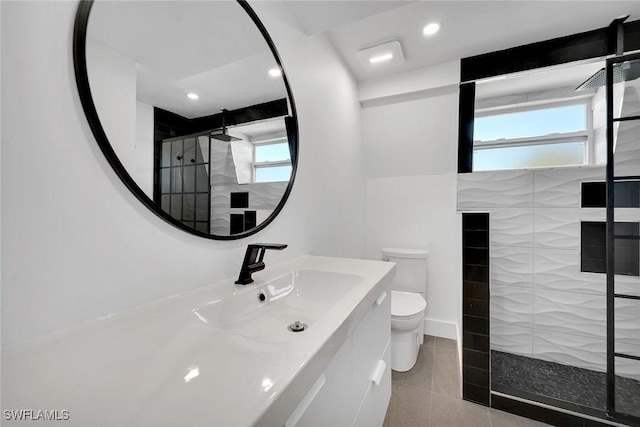 bathroom featuring a tile shower, a wealth of natural light, tile patterned floors, and toilet