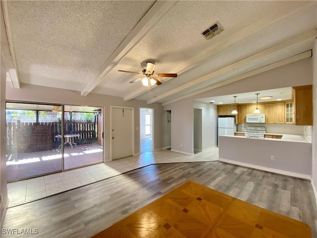 unfurnished living room featuring ceiling fan, lofted ceiling with beams, a textured ceiling, and light hardwood / wood-style flooring