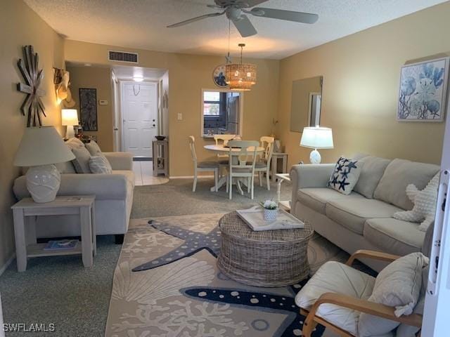 carpeted living room with ceiling fan and a textured ceiling