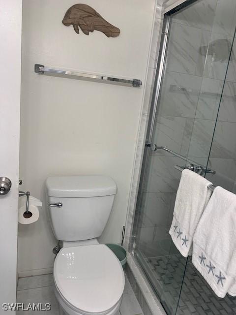 bathroom featuring toilet and a shower with shower door