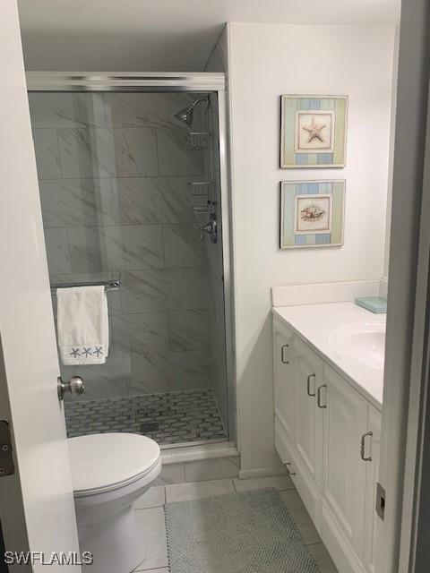 bathroom featuring tile patterned floors, vanity, toilet, and a shower with door