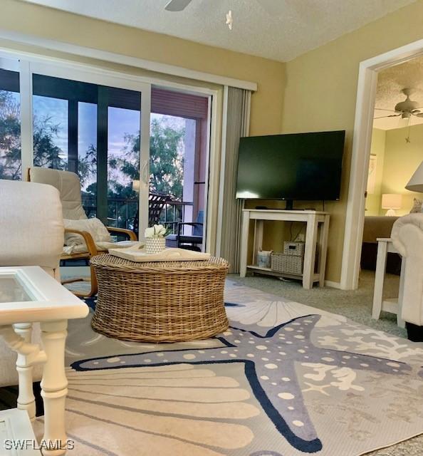 interior space featuring ceiling fan, light colored carpet, and a textured ceiling