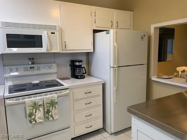 kitchen featuring white cabinets, white appliances, and light tile patterned floors