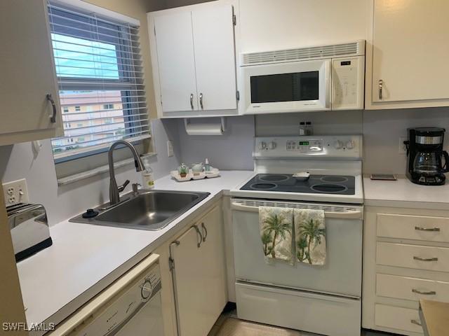 kitchen featuring sink, white cabinets, and white appliances