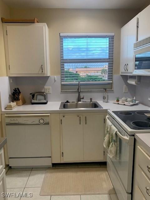 kitchen with sink, white cabinets, white appliances, and light tile patterned floors