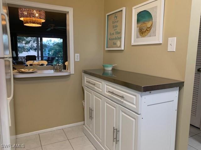 interior space with light tile patterned floors, white refrigerator, and white cabinetry