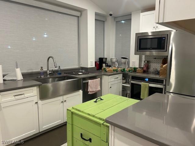 kitchen featuring white cabinetry, sink, stainless steel appliances, and lofted ceiling