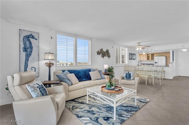 living area with ceiling fan, light tile patterned flooring, baseboards, and crown molding