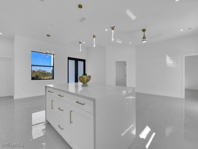 kitchen featuring pendant lighting, ceiling fan with notable chandelier, a kitchen island, light stone counters, and white cabinetry