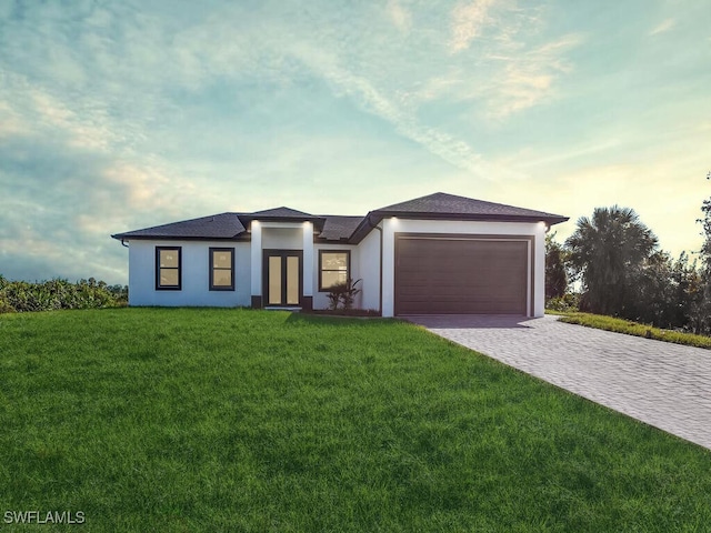 view of front of home with a garage and a lawn