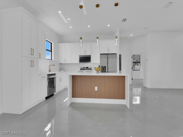 kitchen with a kitchen island, white cabinetry, appliances with stainless steel finishes, and pendant lighting